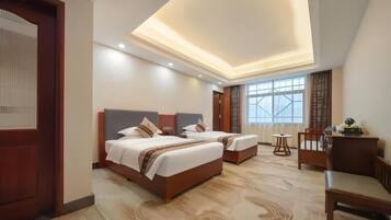 A hotel room with two beds, a desk, and a chair.