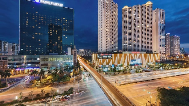 Un paisaje urbano con el Hotel Grand Plaza, edificios altos y una intersección con mucho tráfico.