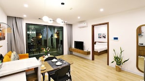 Una habitación de hotel moderna con zona de comedor, televisor y un espejo grande.