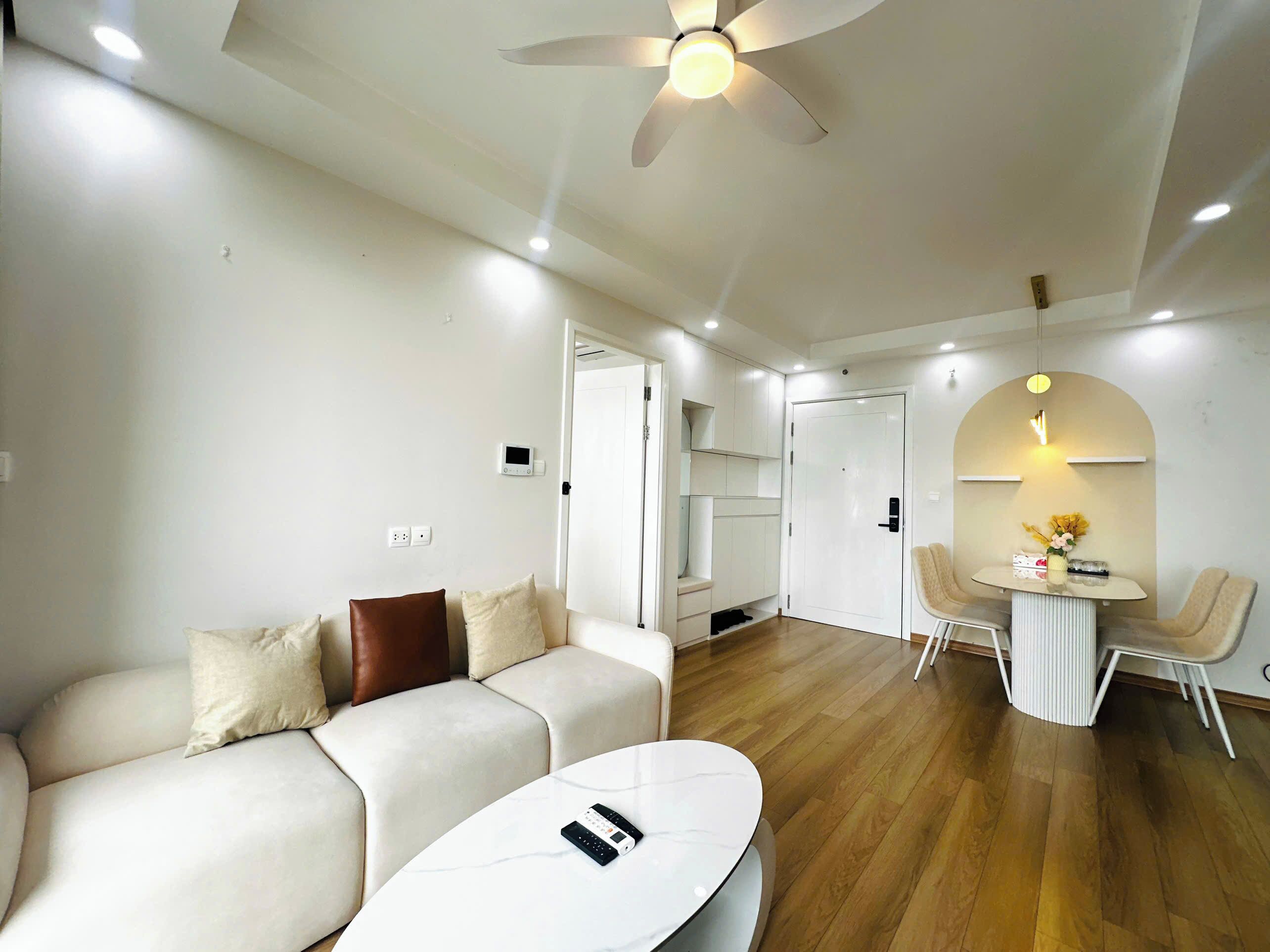 A modern living room with a sofa, a coffee table, a ceiling fan, and a dining area with chairs and a small table.