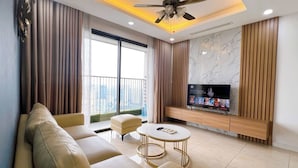 Una sala de estar moderna con sofá, otoman, mesa de centro, televisor y ventilador de techo.