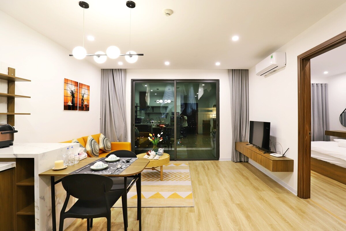 A modern hotel room with a dining area, a TV, and a balcony with a view.