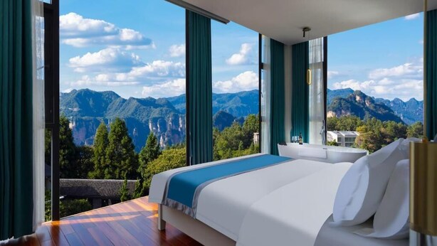Une chambre avec un grand lit, une vue sur les montagnes et un balcon.