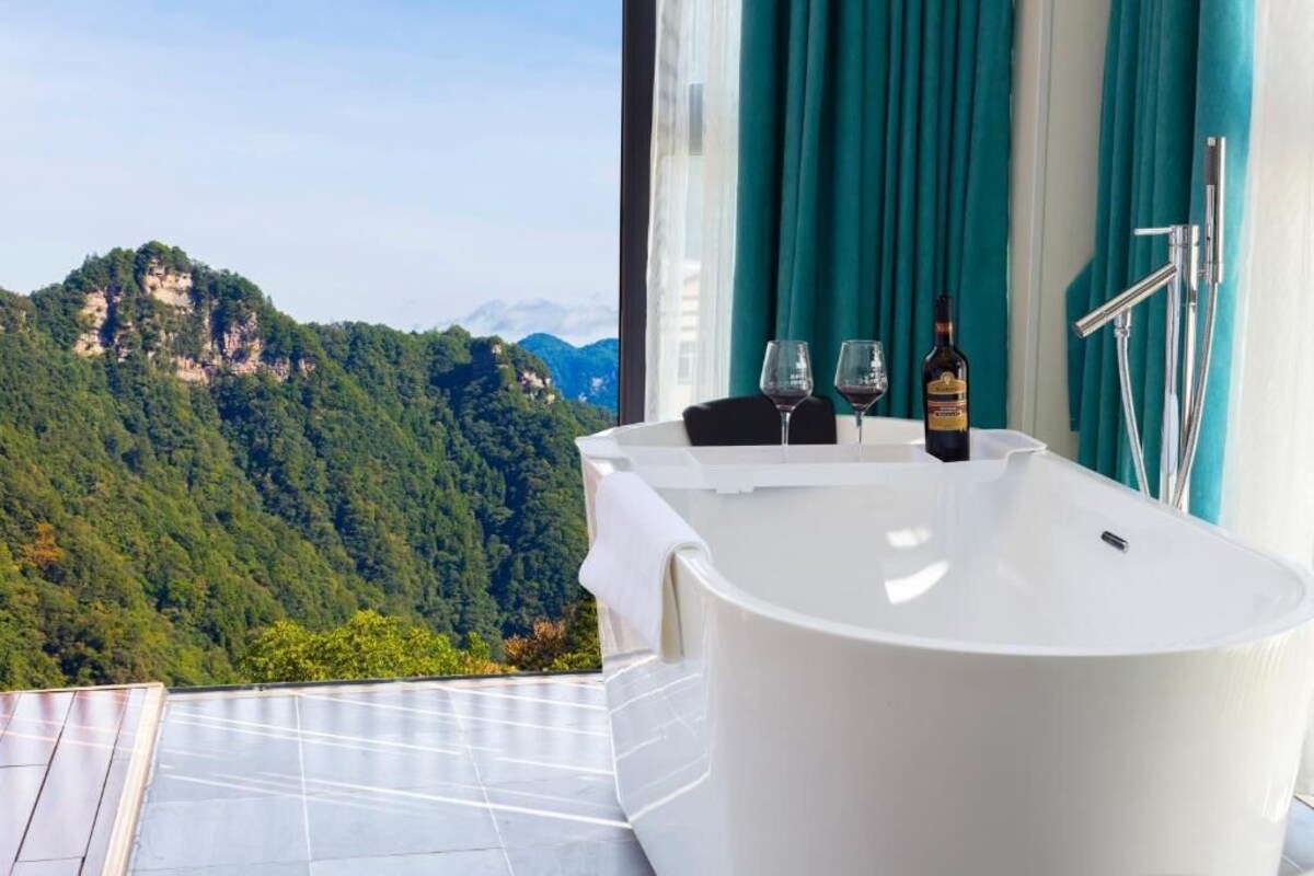 A modern bathroom with a freestanding bathtub, two wine glasses, and a bottle of wine.