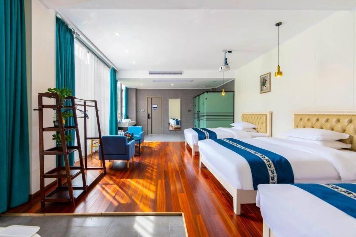 A hotel room with two beds, a desk, a chair, and a large window with curtains.