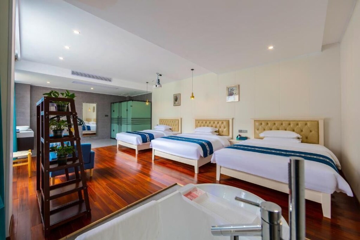 A hotel room with two beds, a wooden ladder, a bathtub, and a view of the outside.