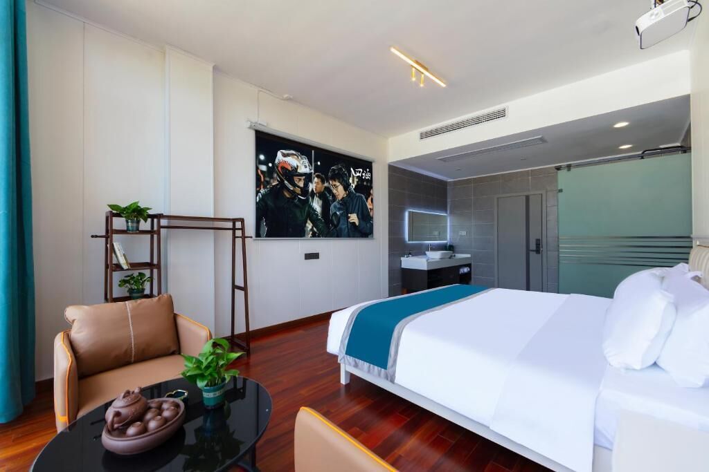 Une chambre d’hôtel moderne équipée d’un lit, d’un bureau, d’une chaise, d’une petite table avec une plante et d’un téléviseur fixé au mur.