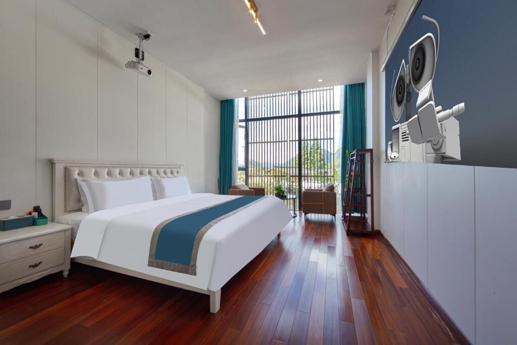 A hotel room with a large bed, a nightstand, a desk, a chair, a bookshelf, and a large window with a view.