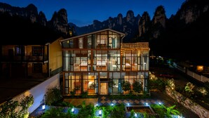 Un hôtel moderne doté d’une façade en verre, de plusieurs étages et offrant une vue sur les montagnes en arrière-plan.