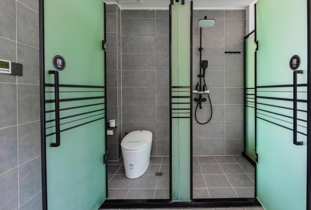 A modern bathroom with a glass partition, a toilet, and a shower area.