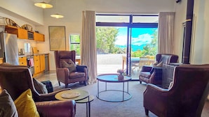 A living room with leather sofas, a coffee table, and a view of a scenic outdoor area. - The Black House Horizon Retreat -Private Outdoor Tub (Lake Tekapo)