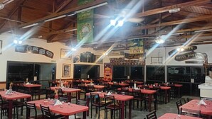 A restaurant with multiple tables and chairs, wooden beams on the ceiling, and various signs and decorations on the walls.
