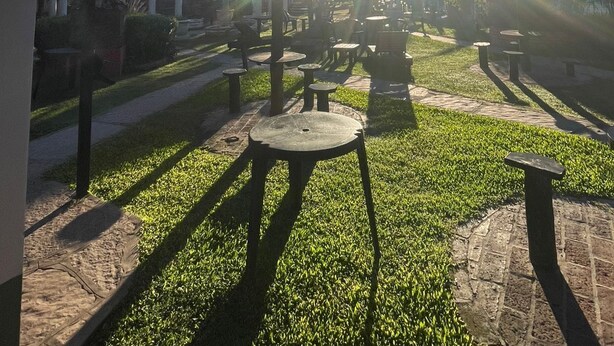 An outdoor seating area with tables and chairs, a clear sky, and sunlight.