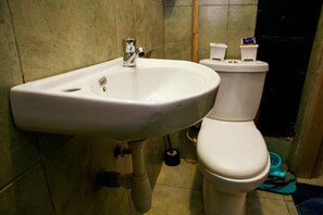 Ein Badezimmer mit einem weißen Waschbecken, einer Toilette und einem Mülleimer.