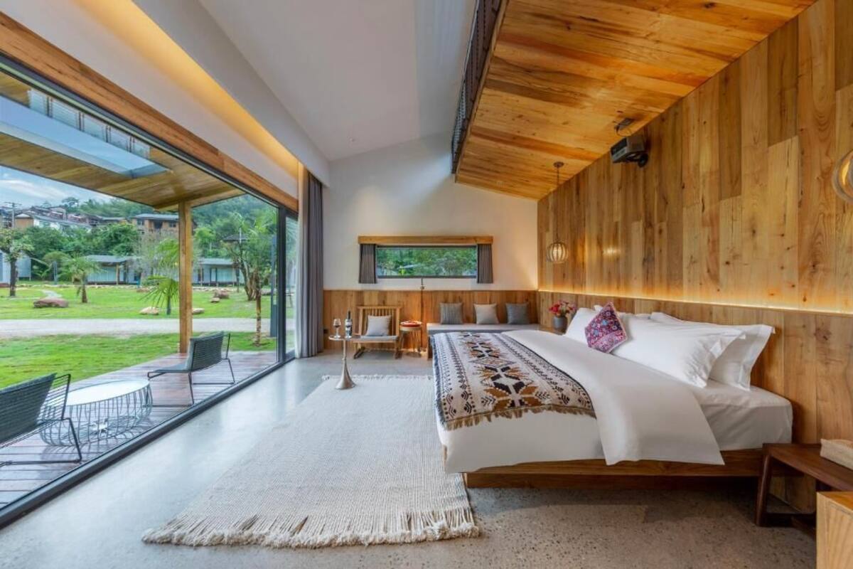Un dormitorio moderno con una cama grande, techo de madera y vistas a un jardín.