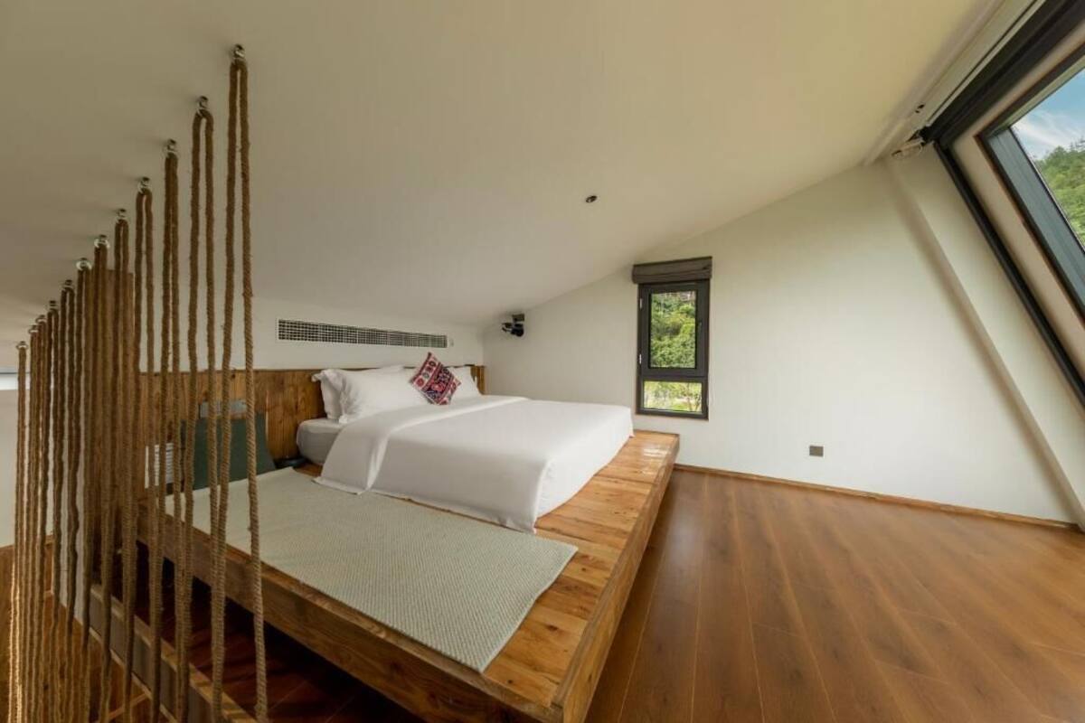 Un dormitorio con cama de madera, una ventana y vistas al verdor.