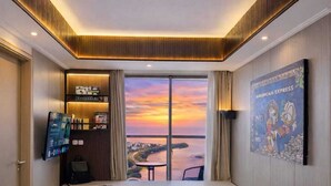 Une chambre d’hôtel avec une grande fenêtre, un lit, une télévision et une petite table.