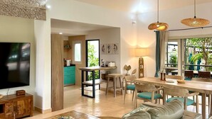 Una sala moderna con sofá, televisor, una mesa de centro de madera y un comedor con mesa y sillas.