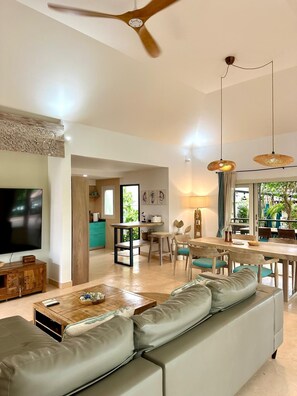 A modern living room with a sofa, TV, wooden coffee table, and a dining area with a table and chairs. - Azure Garden Villa, close to ChoengMon beach (Koh Samui)