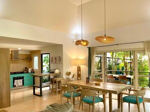 Une cuisine moderne avec un coin repas, de grandes fenêtres et une vue sur la verdure.