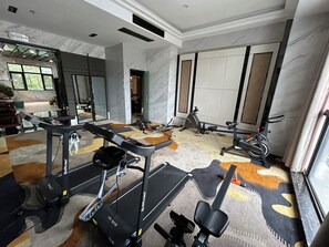 Un gimnasio en casa con cintas de correr, bicicletas estáticas y equipo de ejercicio.