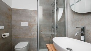Un bagno moderno con doccia vetrata, lavandino bianco e servizi igienici.