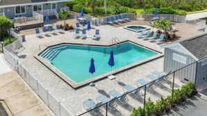 A pool area with lounge chairs and umbrellas, a building with a tower, and a view of the water. - Rare BOCA GRANDE 3BR/3BA WATERFRONT - Gulf Sunsets & Harbor Sunrises - Boat Slip (Boca Grande)