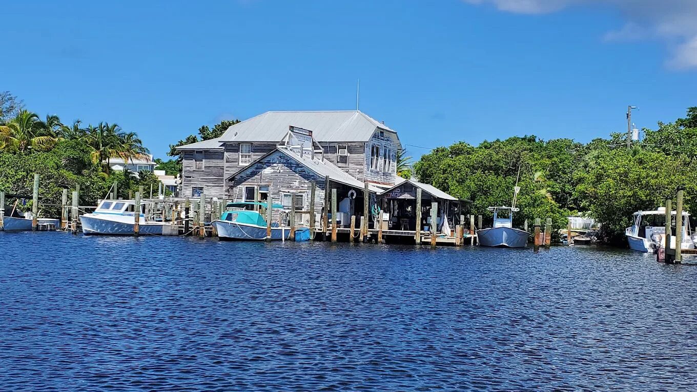A waterfront building with docked boats, wooden walkways, and a clear blue sky.