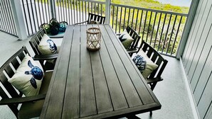 A covered outdoor dining area with a table and chairs, overlooking a beach and marina. - Rare BOCA GRANDE 3BR/3BA WATERFRONT - Gulf Sunsets & Harbor Sunrises - Boat Slip (Boca Grande)