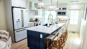 A modern kitchen with a central island, bar stools, and a dining area. - Rare BOCA GRANDE 3BR/3BA WATERFRONT - Gulf Sunsets & Harbor Sunrises - Boat Slip (Boca Grande)