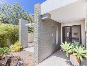 A modern building with a stone facade, a covered outdoor area, and potted plants. - Longboard Coastal Retreat (Tweed)