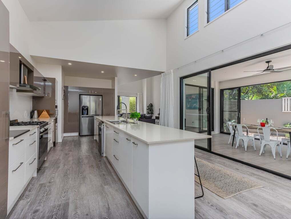 A modern kitchen with a large island, built-in appliances, and a dining area with outdoor seating.