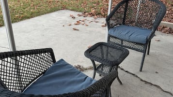 Dos sillas de mimbre con cojines en un patio de concreto.