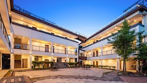 Ein mehrstöckiges Hotel mit Außenbestuhlung und Innenhof.