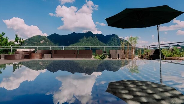 Ein klares Schwimmbecken mit Bergblick, Liegestühlen und einem Sonnenschirm.