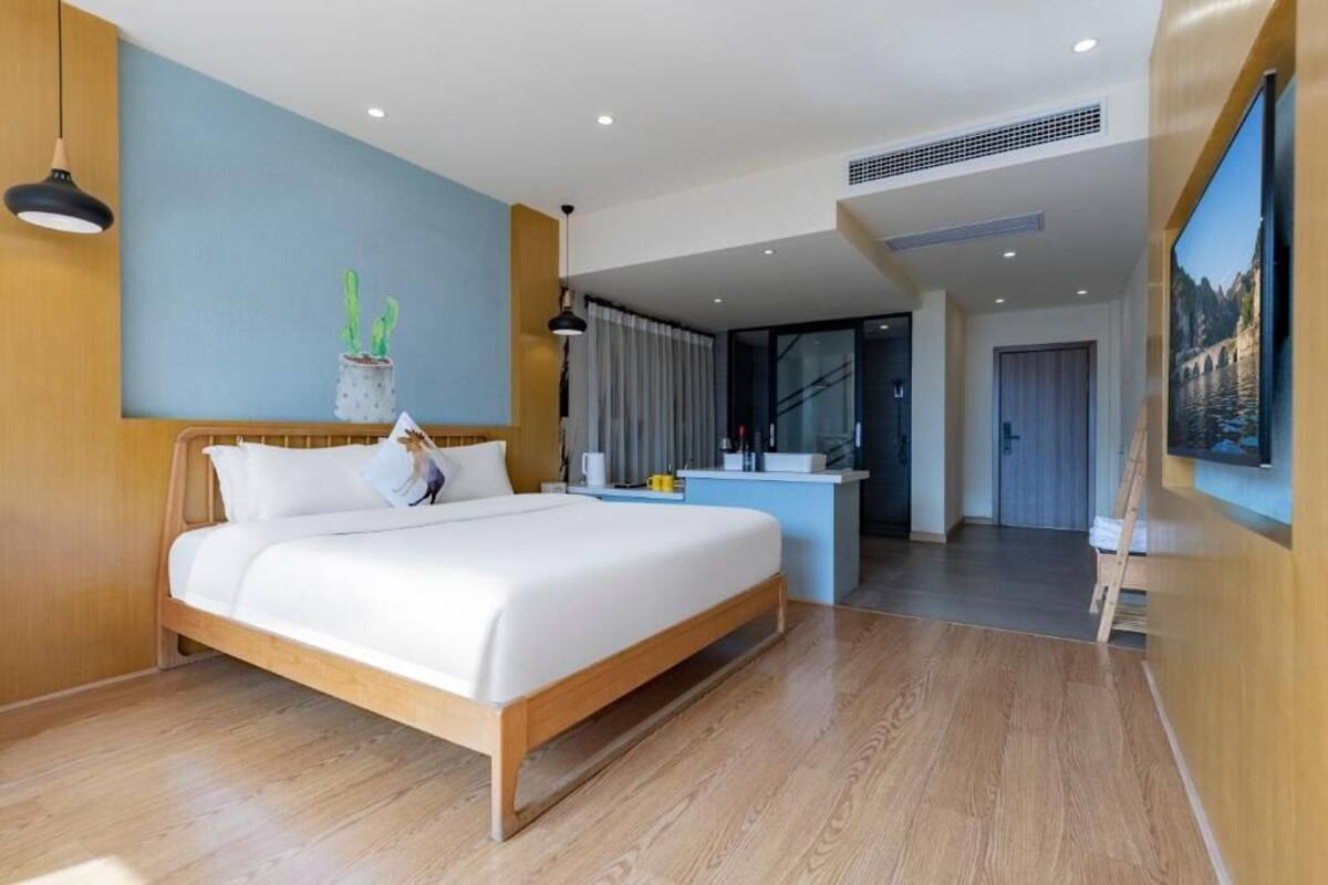 Una habitación de hotel moderna con una cama de madera, un escritorio pequeño, un ventanal grande y vistas al exterior.