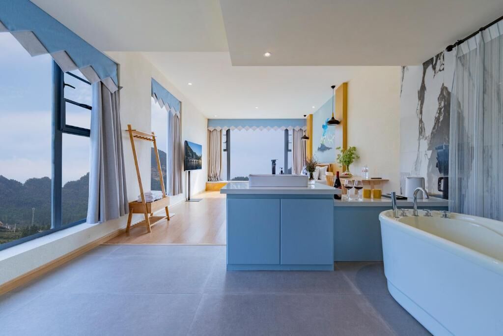 A modern bathroom with a large bathtub, a sink, and a window offering a mountain view.