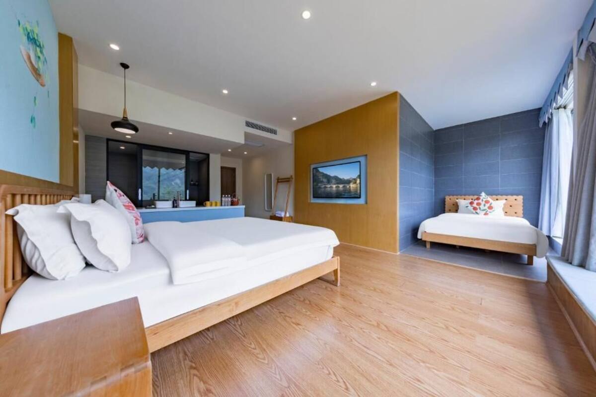 Habitación de hotel moderna con una cama grande, una cama más pequeña, un escritorio y vistas a la montaña.