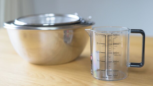A stainless steel bowl and a measuring jug on a wooden surface. - TEMARI Premier NORTH (Hakone)