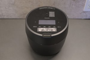 Una olla arrocera Panasonic negra con pantalla digital y botones de control.