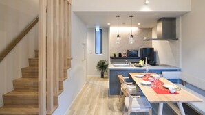 A modern kitchen with a central island, wooden staircase, and pendant lighting. - TEMARI Premier NORTH (Hakone)