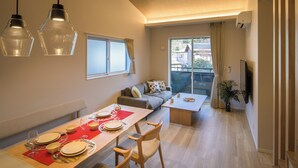 A modern living room with a dining area, a sofa, a TV, and a large window. - TEMARI Premier NORTH (Hakone)