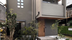 A modern two-story building with a balcony, a small garden area with plants, and a concrete pathway leading to the entrance. - TEMARI Premier NORTH (Hakone)