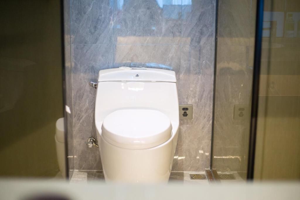 A toilet in a bathroom with a marble wall.