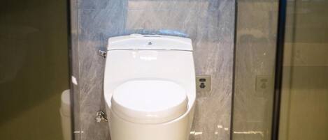 A toilet in a bathroom with a marble wall.