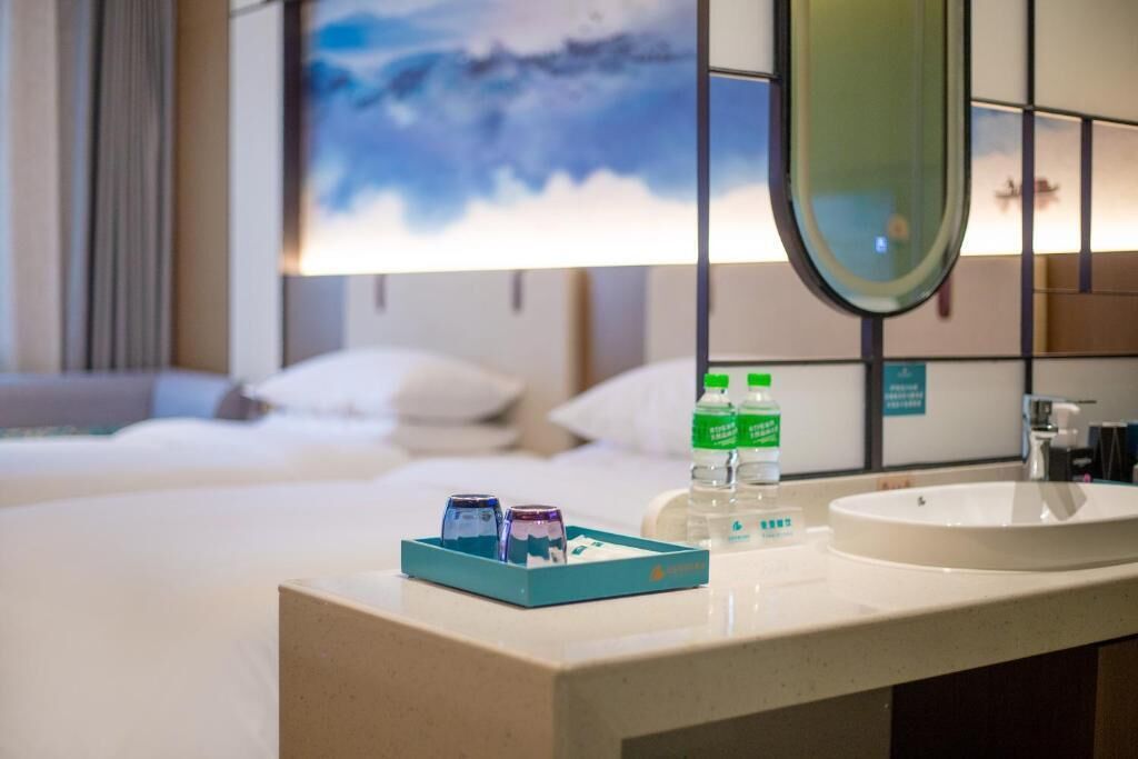 Une chambre d’hôtel comprenant un lit, une salle de bain avec un lavabo et un miroir, et un plateau avec des articles de toilette.