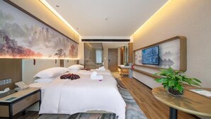 A hotel room with a large bed, a desk with a telephone, a small table with a plant, and a painting on the wall. - Friend Zhangjiajie Hotel (Zhangjiajie)