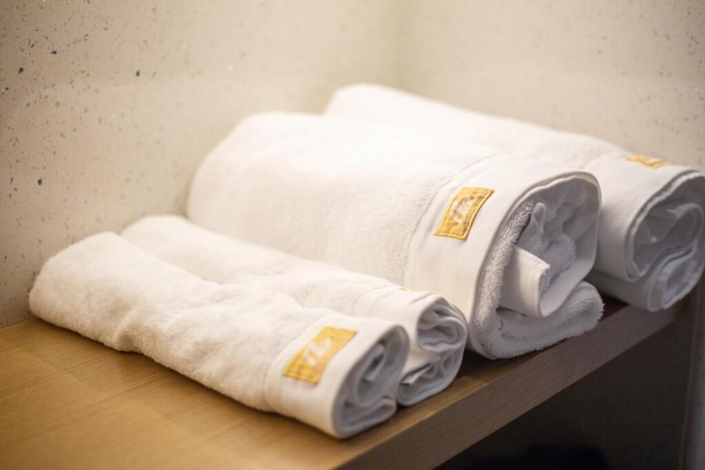 A set of neatly folded white towels with a gold emblem on a wooden shelf.