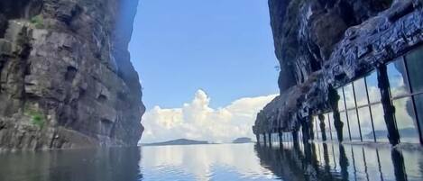 A clear view through a natural rock arch into a calm body of water with a distant island.