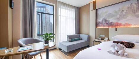 A hotel room with a bed, a desk, a chair, a sofa, a painting, and a window with curtains.
